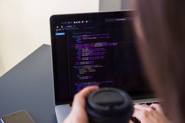 İşyerindeki bir dizüstü bilgisayarda kodlama yapan bir programcı