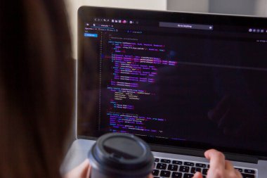 İşyerindeki bir dizüstü bilgisayarda kodlama yapan bir programcı