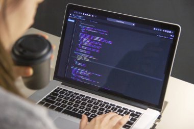 İşyerindeki bir dizüstü bilgisayarda kodlama yapan bir programcı
