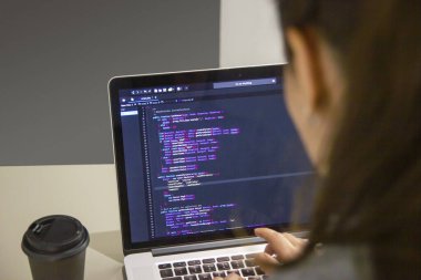 İşyerindeki bir dizüstü bilgisayarda kodlama yapan bir programcı