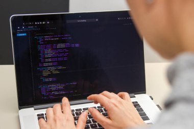 İşyerindeki bir dizüstü bilgisayarda kodlama yapan bir programcı