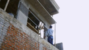 Çatıda vinç olan inşaat işçisi.