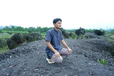 Genç adam yerde oturuyor ve gülümsüyor..