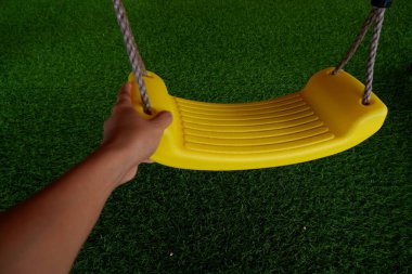 Yeşil çimlerin üzerinde sarı bir ip olan çocuk parkı.