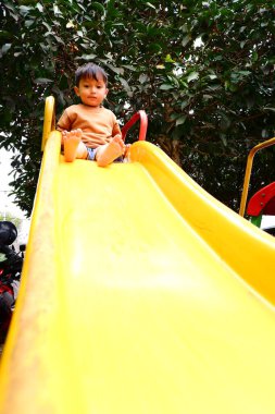 Çocuk parkta slaytla oynuyor.