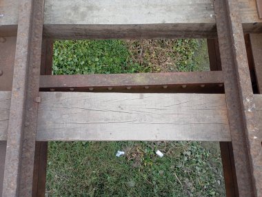 Çimenli bölge üzerinde paslı metal ve ahşap köprü yapısı