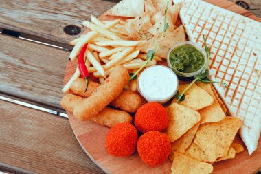 Ahşap arka planda hazır yemek. Quesadilla, cips, patates kızartması ve peynir topları.. 