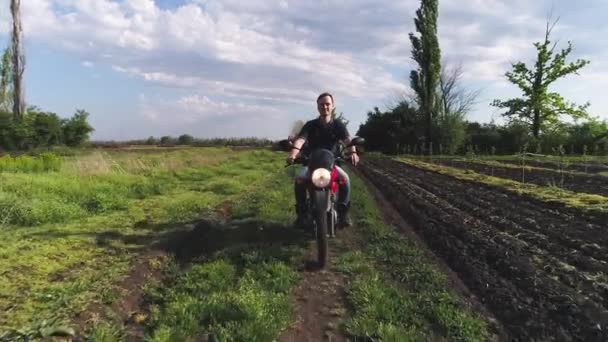 Jongeman op een motorfiets op landbouwgebied — Stockvideo