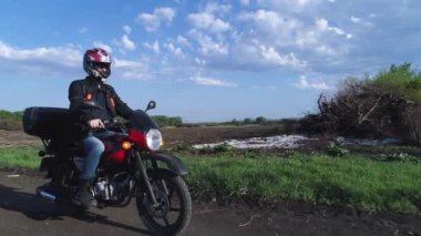 Köy yolunda motosikletli genç bir adam. Tarım alanları