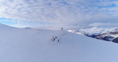Bir kadın karlı bir yamacı fotoğraflıyor. Kozalaklı ağaçlar karla kaplıdır. Bulutlar vadi boyunca yüzer. Kafkas Dağları Arkhyz 2020 'de Karlı Tepeler Turistler