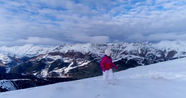 幸せな女の子は雪の山のピークを登る — ストック動画