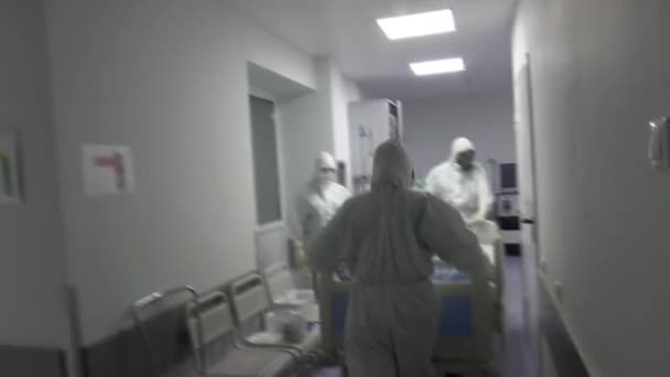 보호 복을 입은 간호사 가 병원 복도를 따라 Covid-19 환자와 함께 들것을 들고 다닌다. — 비디오