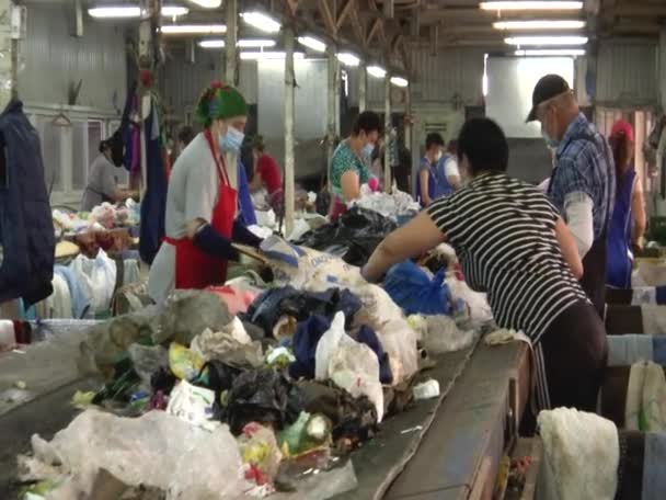 Onherkenbare arbeiders aan de transporteur voor het sorteren van afval in de afvalverwerkingsfabriek van Kopanskaya, Rusland - 10 augustus 2021 Stockvideo's