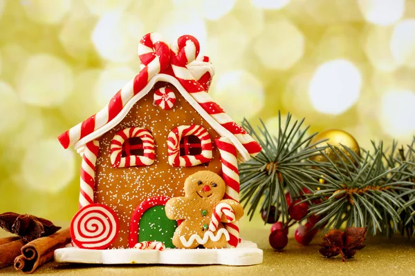 Festive magic Christmas sweet gingerbread house and Christmas decoration with golden bokeh lights on background.