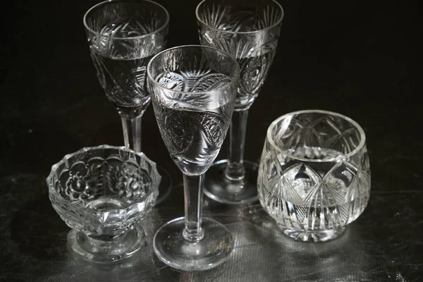 Set of crystal tableware with pure water on dark background.