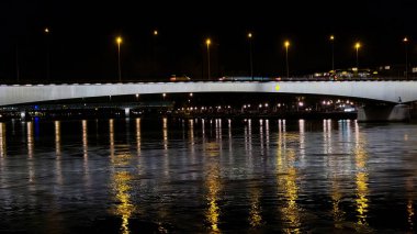 Nehirde yansıması olan modern bir köprünün gece görüşü