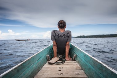 Adam Oturan Doğal Ahşap Uzun Kuyruk Tekne Karayip Okyanusu Fotoğraf. Temiz su ve bulutlar ile mavi gökyüzü. Yatay.