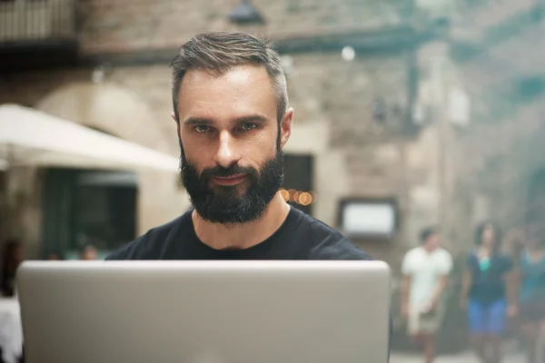 Closeup Portrait Handsome Bearded Businessman Wearing Black Tshirt Working Laptop Urban Cafe.Young Manager Work Notebook Outdoor Place.Coworking Process Business Startup.Blurred Background. Stock Photo