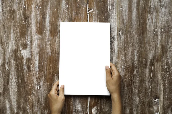 Closeup Blank White Paper Sheet Mockup segurando as mãos masculinas Fundo de mesa de madeira natural. Canvas vazias pintadas Brown Desk . — Fotografia de Stock