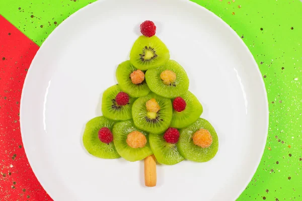 Christmas tree made of kiwi slices on winter color table. — Stock Photo, Image
