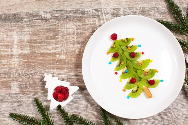 stock image Christmas tree made of kiwi slices on wooden table.