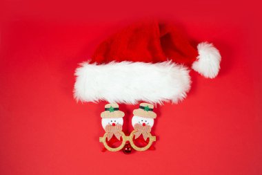 Kırmızı arka planda Noel şapkası ve komik gözlükleri olan şenlikli bir arkaplan. Yeni normal Xmas kavramı.