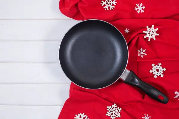 Frying pan or skillet with snowflaks and red tablecloth — Stock Photo, Image