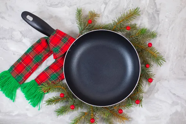 Frying pan or skillet around christmas tree on on marble table — Stock Photo, Image