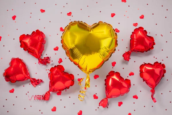 Een grote gele en vele kleine rode luchtballonnen van hartvormige folie — Stockfoto