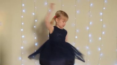 Küçük beyaz kız, şenlik duvarının yanında kollarını açmış dönüyor..