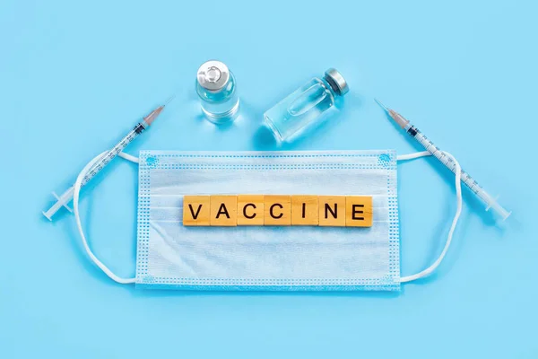 Word Vaccine on protective mask and Vaccines and syringes,