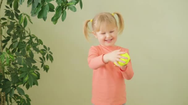 놀고 있는 귀여운 작은 소녀가 서서 옆으로 누런 노란 점액을 뻗고 있습니다. — 비디오