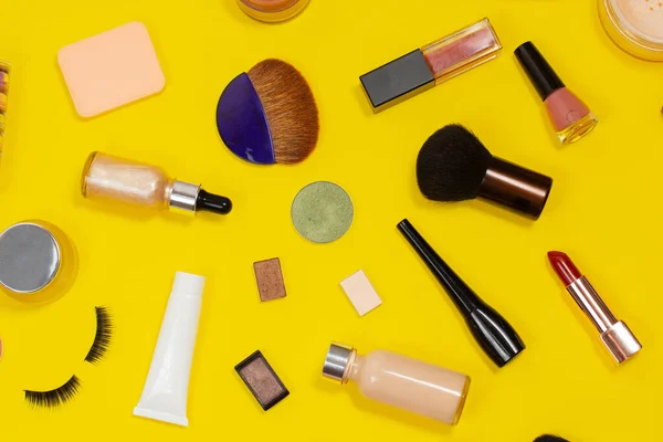 Set of decorative cosmetics on yellow background. Makeup cosmetics tools background