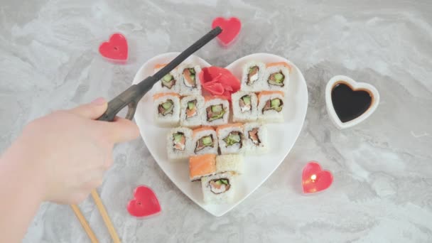 Anzünden von Kerzen im romantischen Valentinstag-Kerzenlicht und einem Set mit Sushi in einem herzförmigen Teller . — Stockvideo