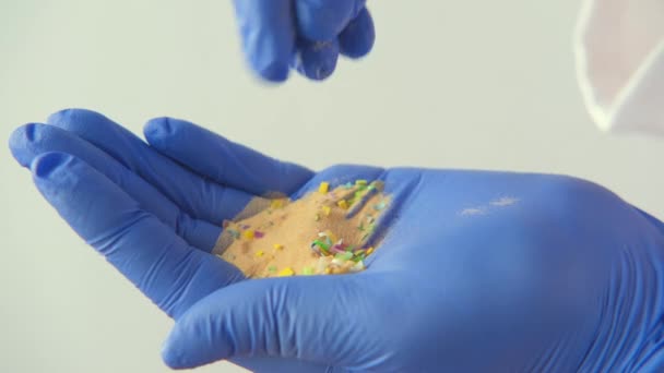 Рука в резиновой перчатке держит песок с микропластиковыми частицами. — стоковое видео