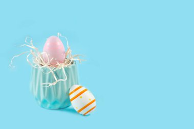 Mavi arkaplanda renkli paskalya yumurtaları ve mavi vazo,