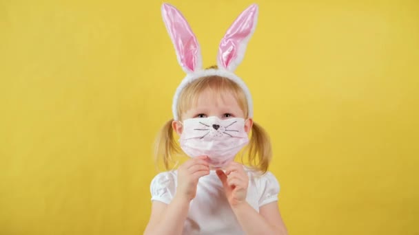 Ritratto di allegra bambina bionda con orecchie da coniglio e maschera protettiva — Video Stock