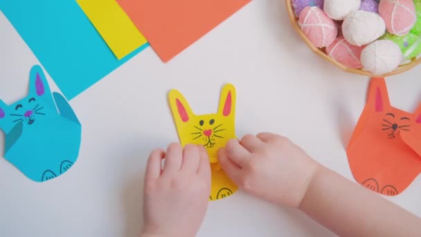 Дети открывают и закрывают лапы бумажному кролику — стоковое видео