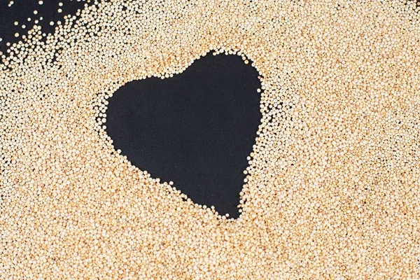 Marco en forma de corazón hecho de semillas de quinua blanca orgánica sobre fondo negro. — Foto de Stock