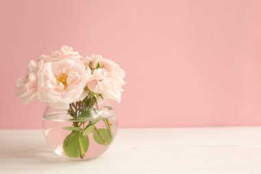 Şeffaf vazoda pembe pastel arka planda şeffaf güller..