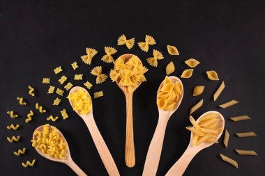 Masadaki tahta kaşıklarda farklı makarna tipleri..