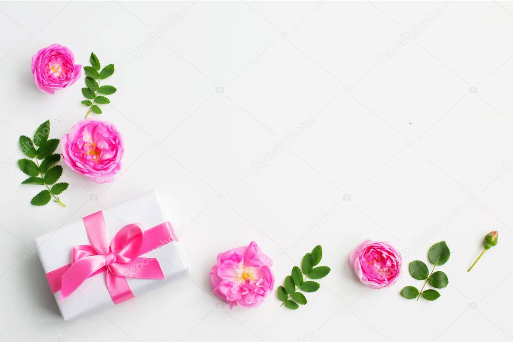 Gift and pink rose flowers on white background.