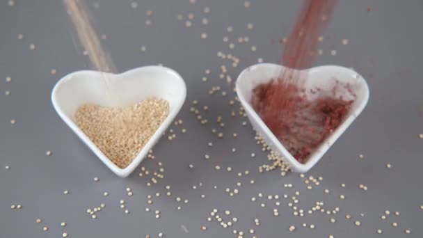 Red and white Quinoa falling in heart-shaped bowl — Stock Video