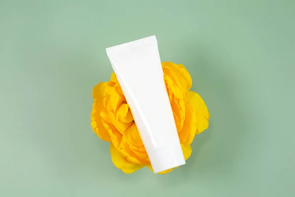 Tubo cosmético blanco encima de una hermosa flor — Foto de Stock