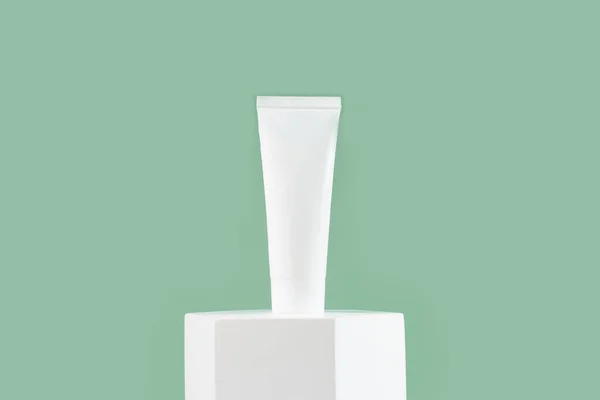Witte cosmetische buis voor huidverzorging gezicht, lichaam op wit podium op groene achtergrond.. — Stockfoto