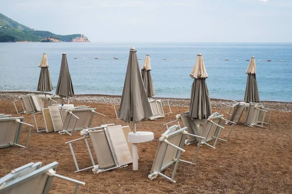 Inverted sun loungers under umbrellason the pebble beach by the sea — Stock Photo, Image