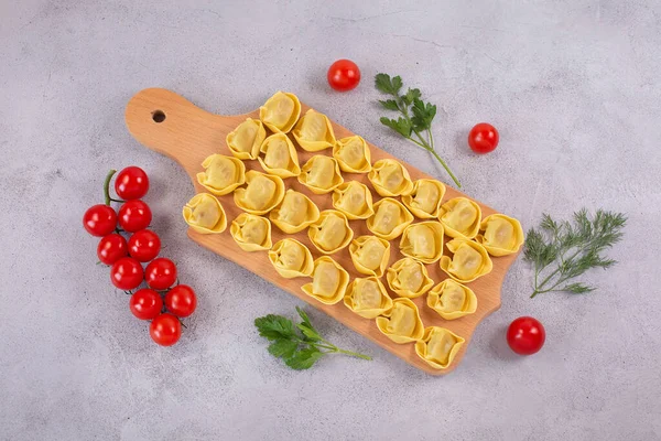 Kypsentämättömät tortelloni sienellä täyttö puulaudalla. — kuvapankkivalokuva