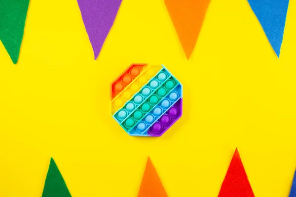 Antistress pop it toy. Rainbow silicone sensory fidget on colorfull background.