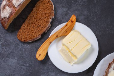 Tereyağlı ekmek ve siyah arka planda tahta bir tereyağı bıçağı.