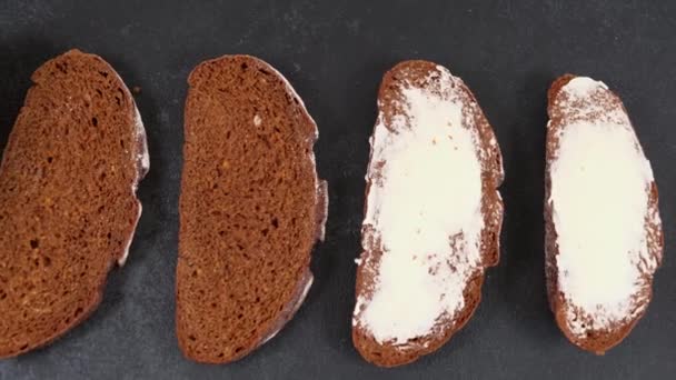 Färskt bakat skivat hantverksbröd med smör på mörk bakgrund — Stockvideo